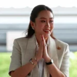 Young woman with folded hands, representing Thailand Prime Minister, showing a respectful and thoughtful gesture