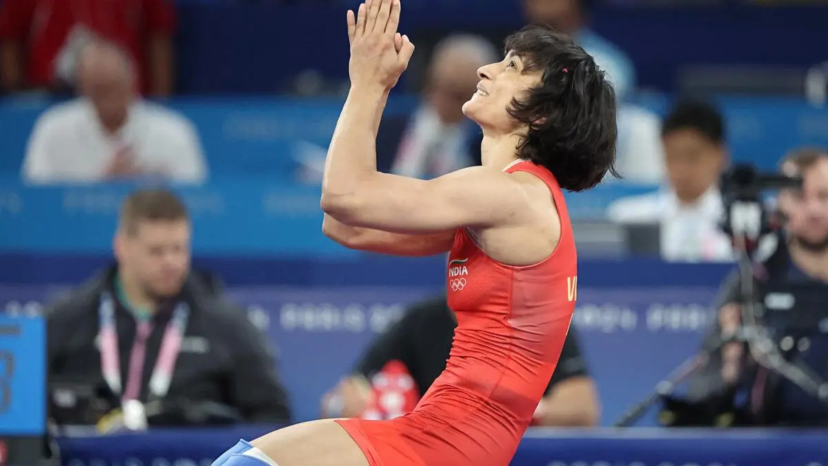 Vinesh Phogat, Indian athlete, sitting on a wrestling mat with folded hands, showing focus and determination